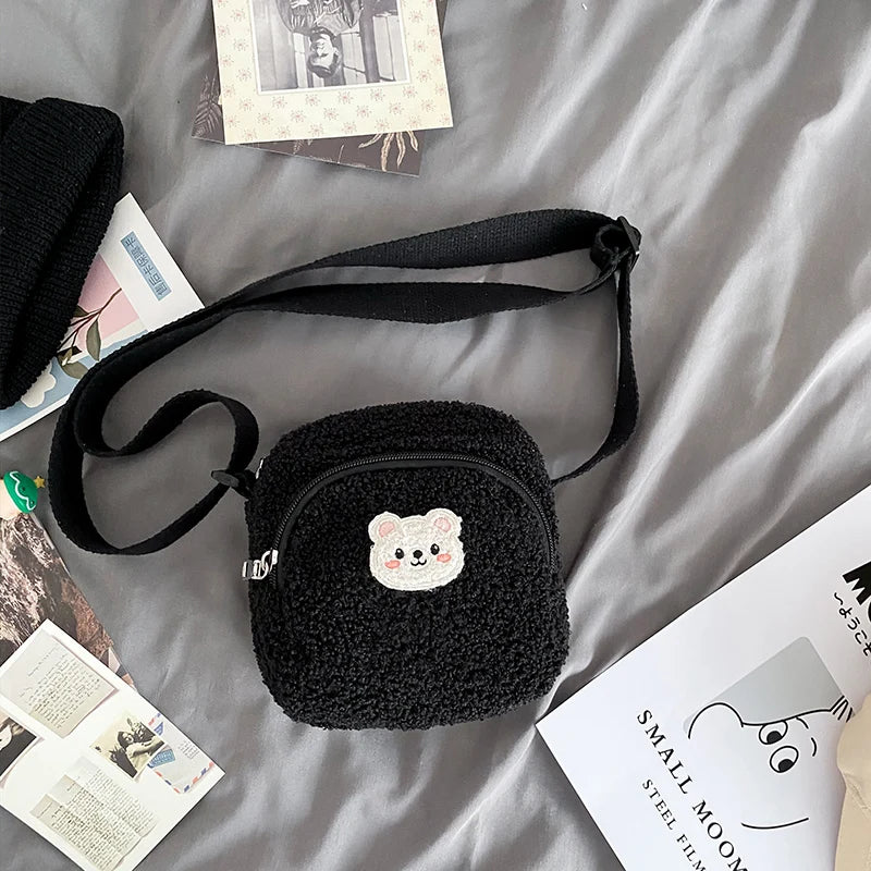 Black textured bag with a Kawaii bear emblem on a gray surface with scattered papers.