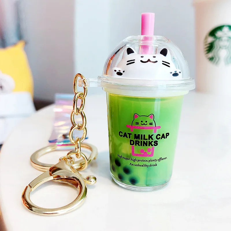 Keychain shaped like a kawaii green milk cap drink with a cat design, featuring a straw and lid.
