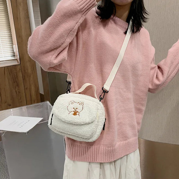 Person wearing a pink sweater with a small white bag featuring a Kawaii cartoon character.