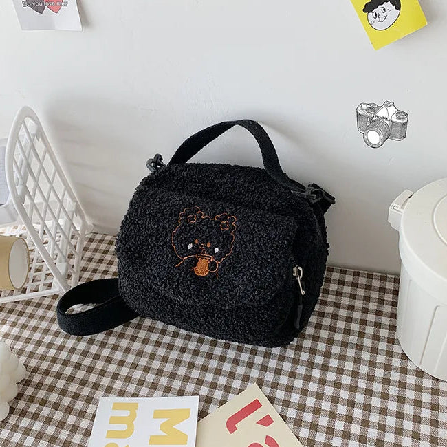Black textured bag with Kawaii bear embroidery on a checkered tablecloth
