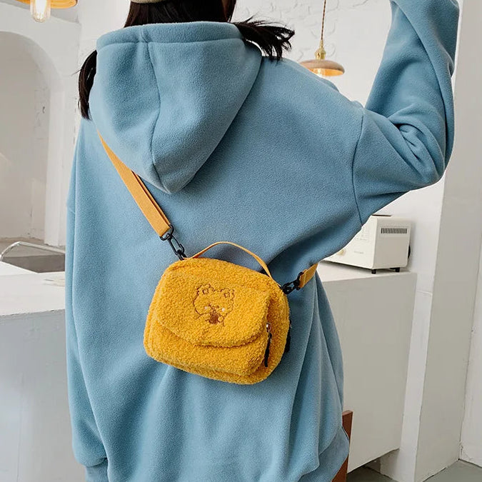 Person wearing a blue hoodie with a yellow fluffy bag featuring a Kawaii bear design.