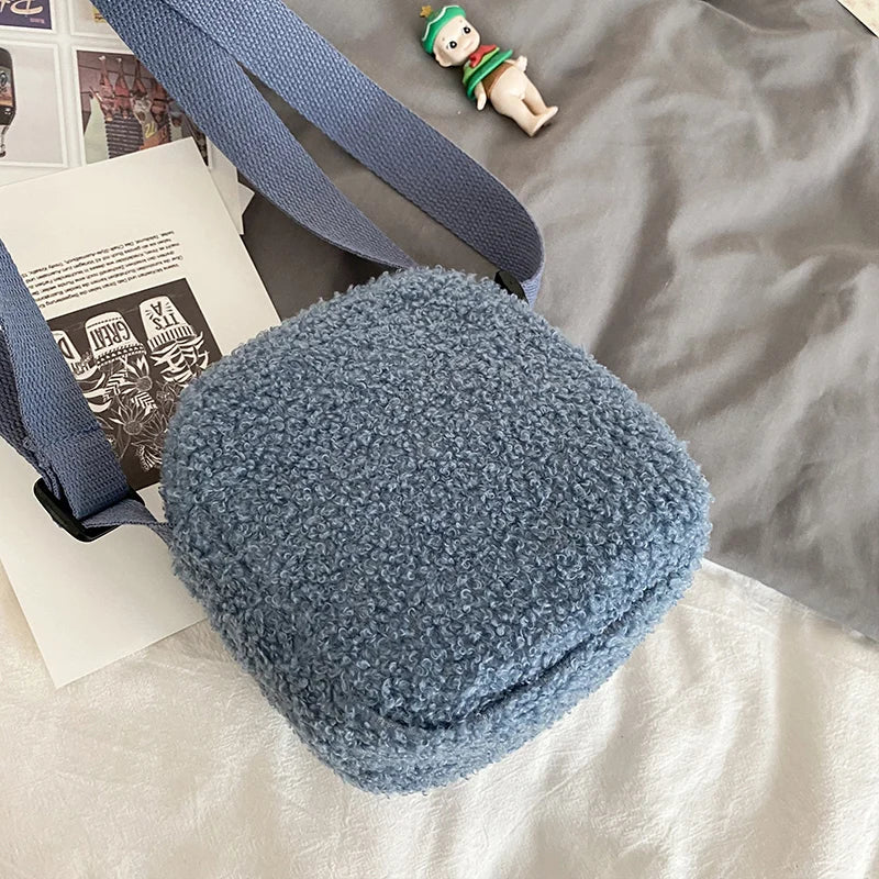 Blue textured Kawaii-inspired crossbody bag on a surface with a small figurine and newspaper in the background