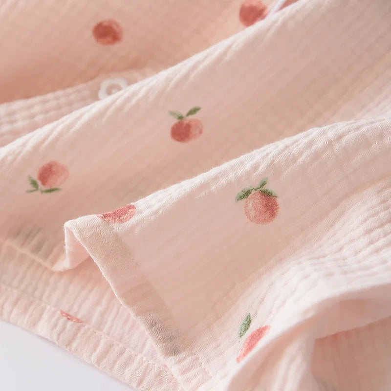 Stack of pink textured fabric with embroidered peach kawaii designs on a white background