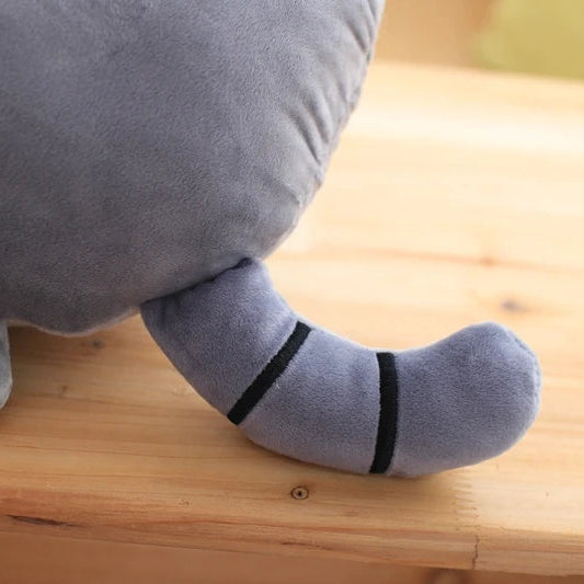 Gray plush kawaii toy with black stripes on a wooden surface