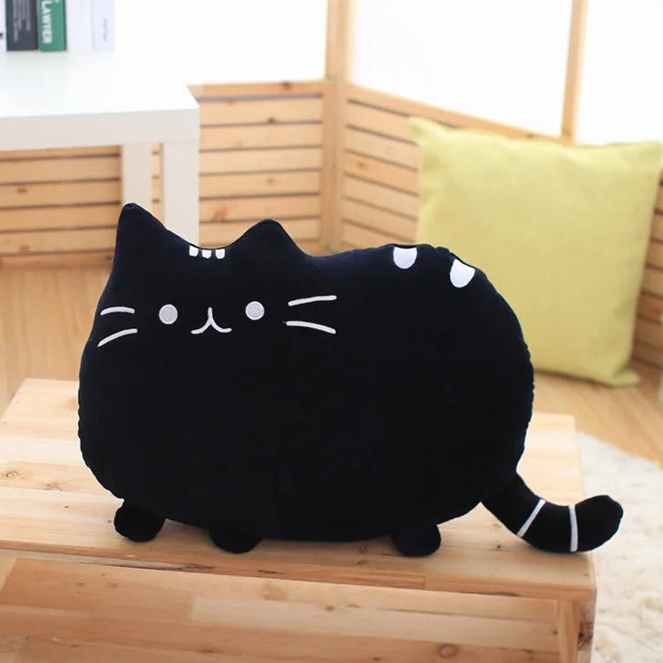 Black cat-shaped plush kawaii toy on a wooden surface with a blurred indoor background