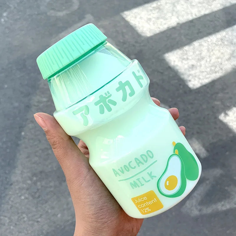 Hand holding a Kawaii bottle of avocado milk with a green cap against a blurred background