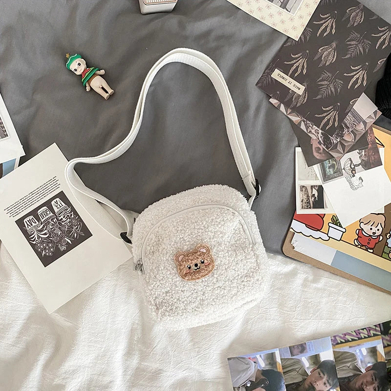 Small white bag with a Kawaii bear emblem on a bed with scattered photos and stationery items.