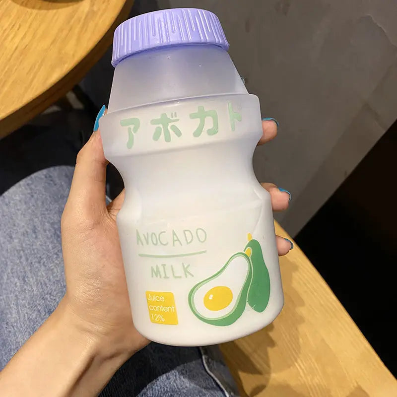 Hand holding a Kawaii-style bottle of avocado milk with a purple cap.