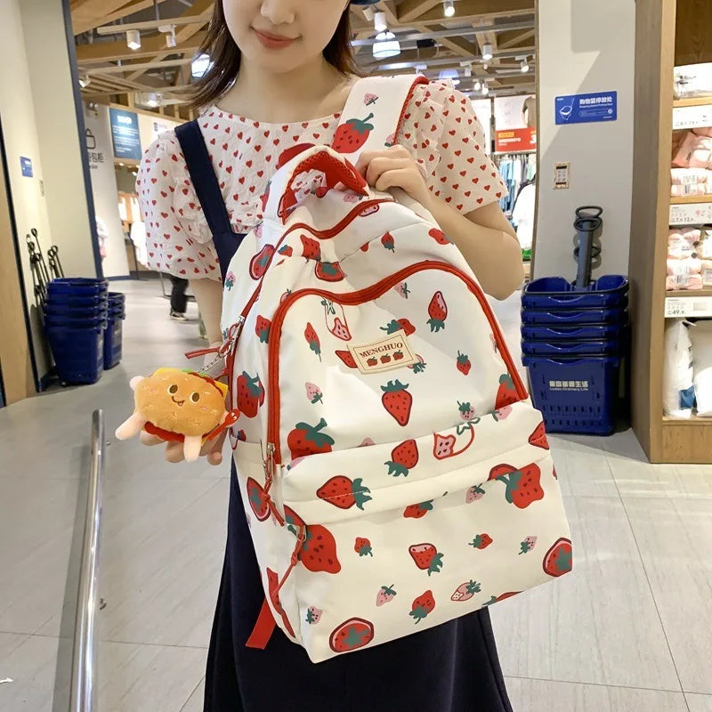 Person holding a Kawaii strawberry-patterned backpack in an indoor setting
