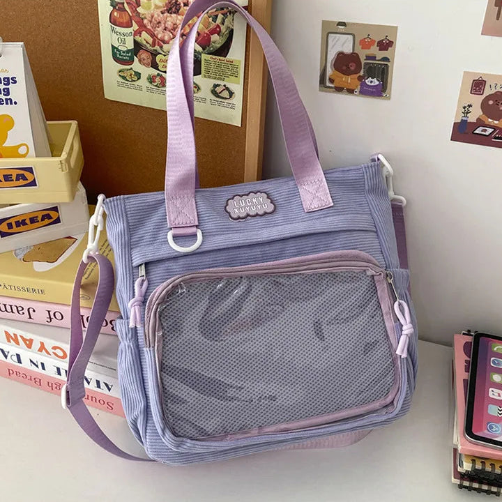 Purple Kawaii bag with pink straps on a surface with books and magazines in the background