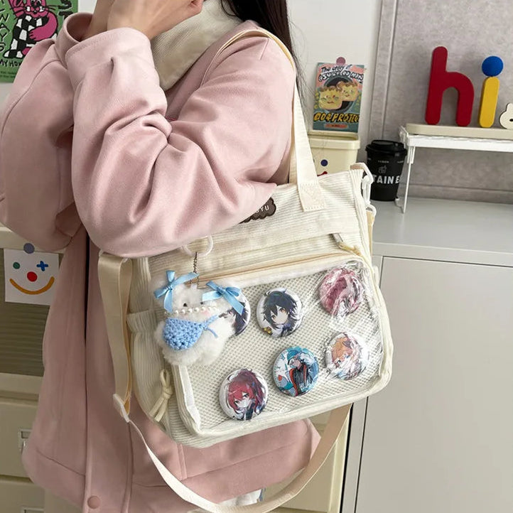 Person holding a beige Kawaii bag with anime character buttons and a plush toy.