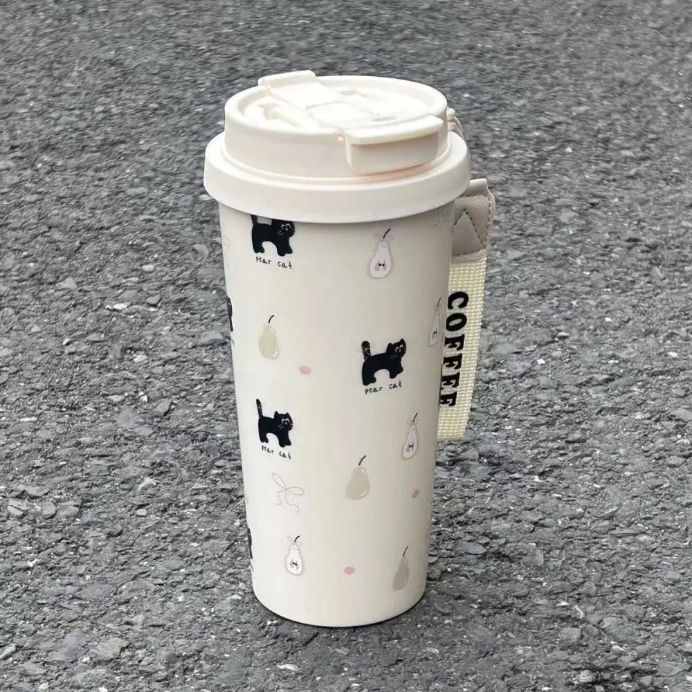 White tumbler with black Kawaii cat illustrations on a gray pavement