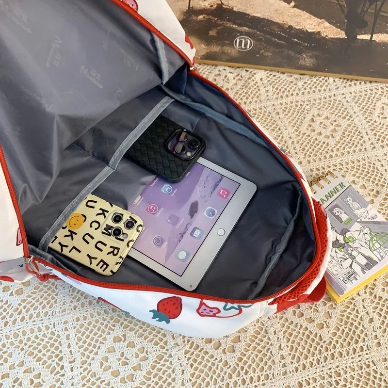 Open Kawaii-designed backpack with electronic devices on a textured surface