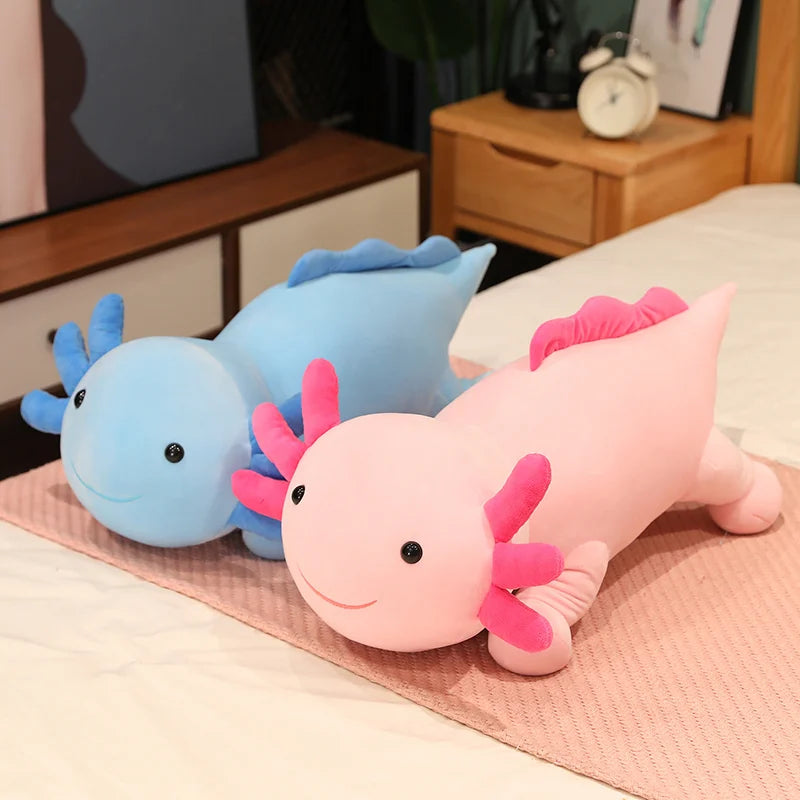 Two axolotl plush kawaii toys, one pink and one blue, on a pink blanket.