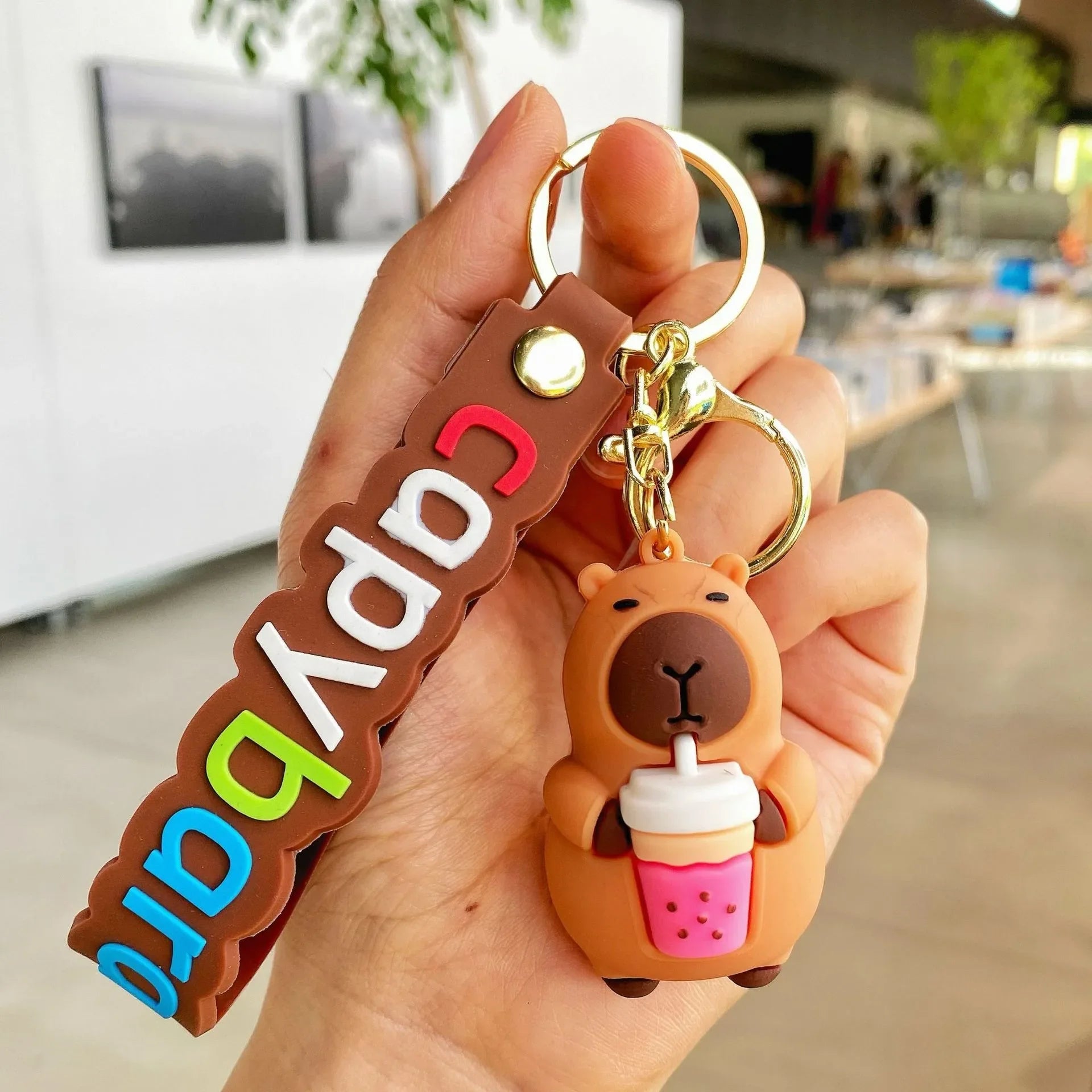 Hand holding a kawaii keychain with a bear design and colorful text