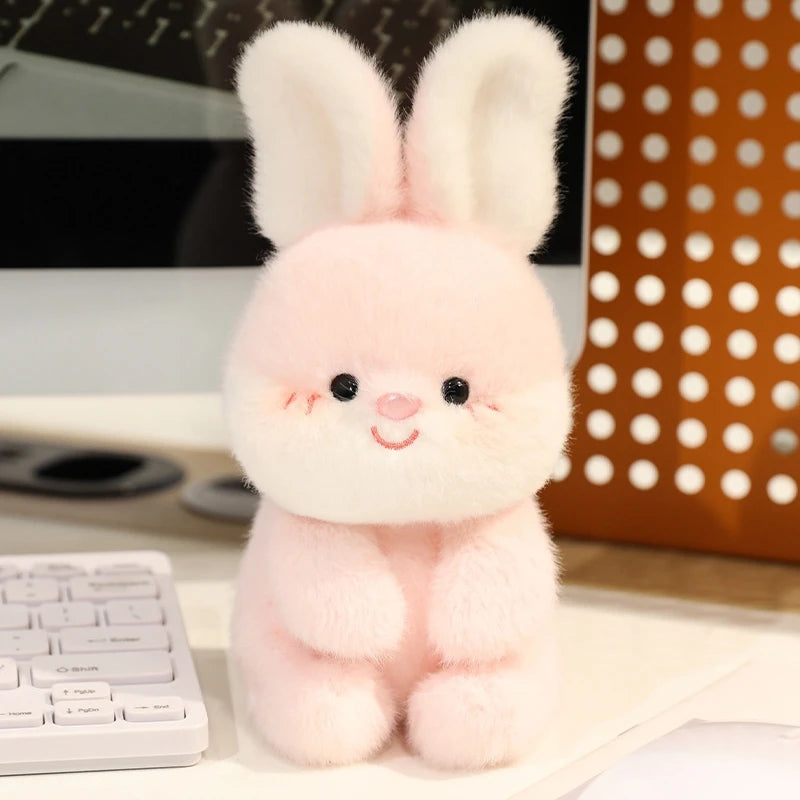 Pink plush bunny kawaii toy on a desk with a computer keyboard and polka dot lamp in the background