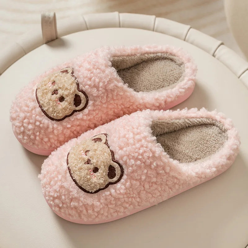 Pair of pink slippers with kawaii bear face designs on a light background