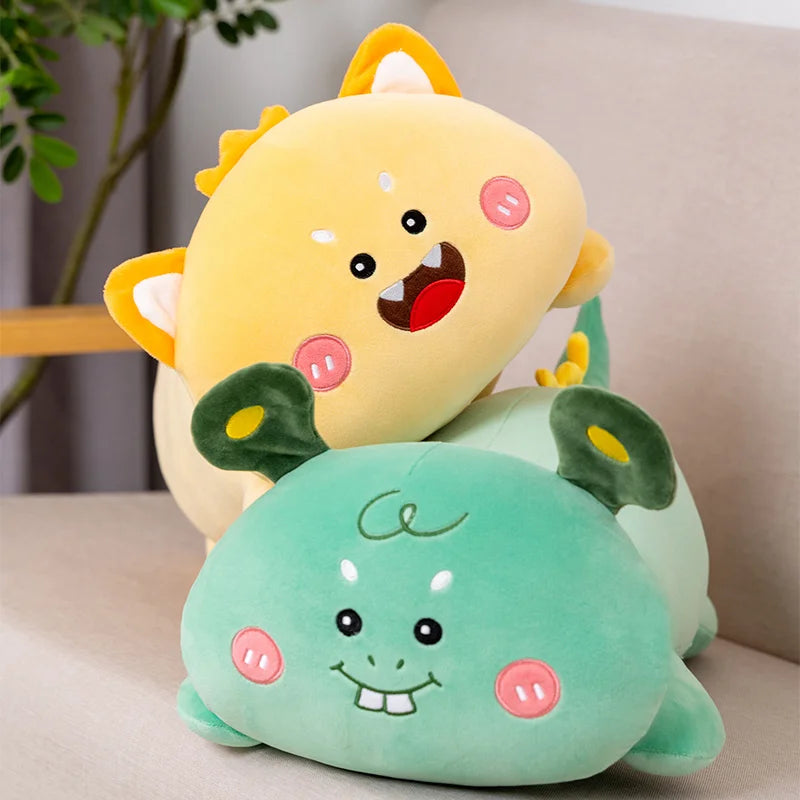Two kawaii plush toys, one yellow and one green, on a light-colored surface with a plant in the background.