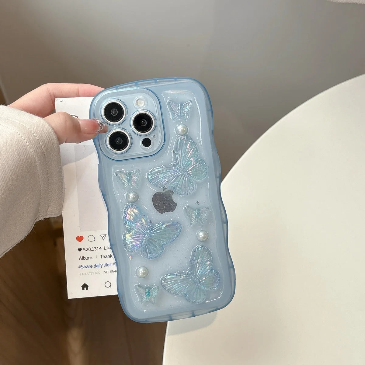 Phone case with kawaii butterfly design held by a hand against a neutral background