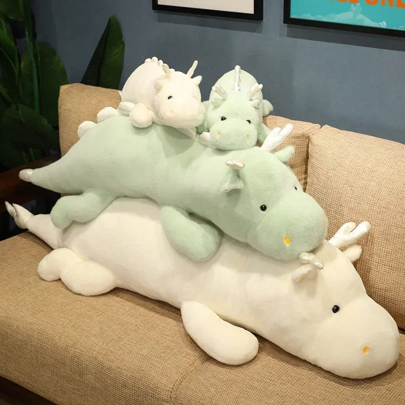 Set of plush kawaii dragon toys on a couch with a neutral background