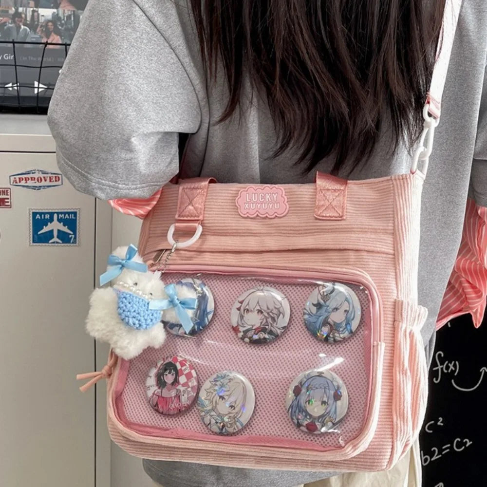 Person holding a pink bag with anime-themed buttons and a Kawaii keychain.