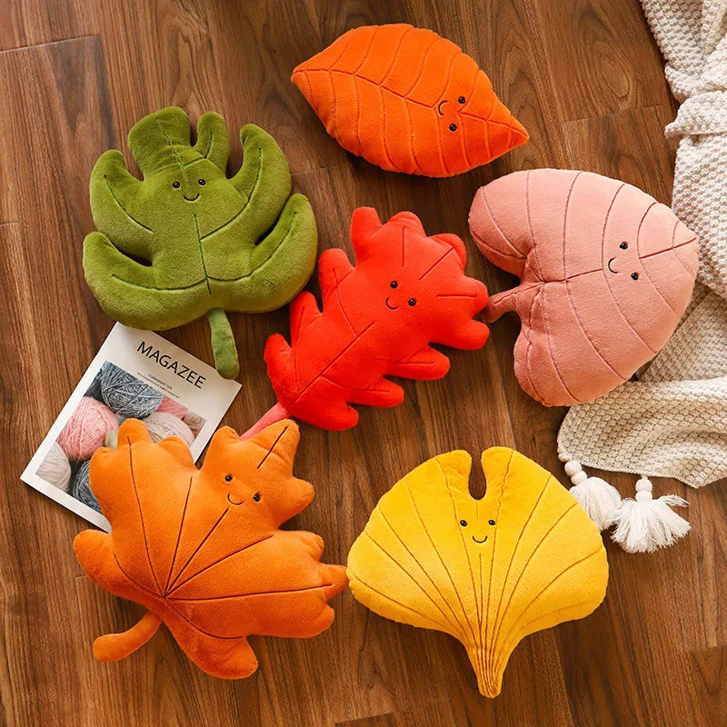 Colorful leaf-shaped kawaii plush toys on a wooden surface with a magazine.