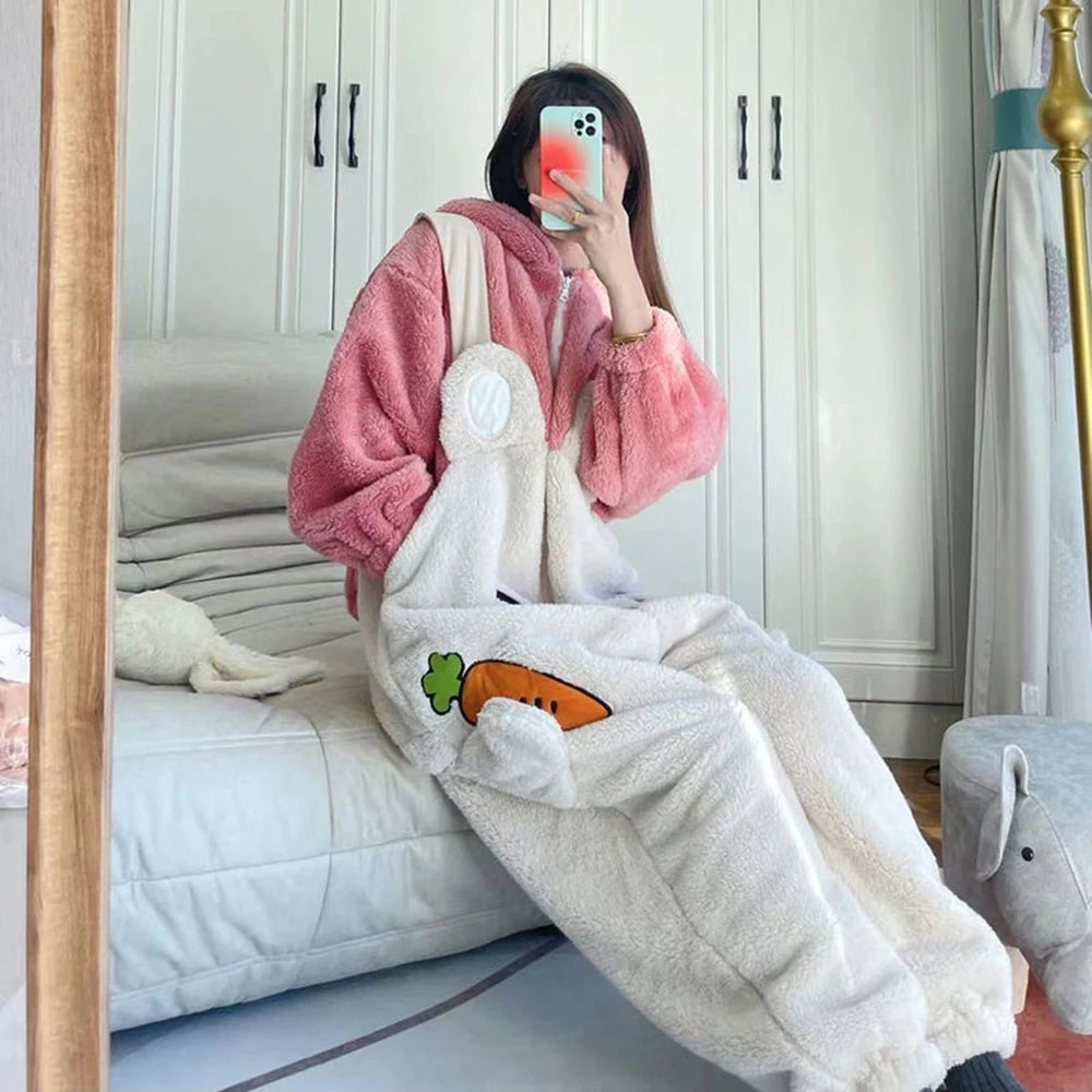 Person wearing a pink robe and white fleece pants with a kawaii carrot design, sitting on a bed.