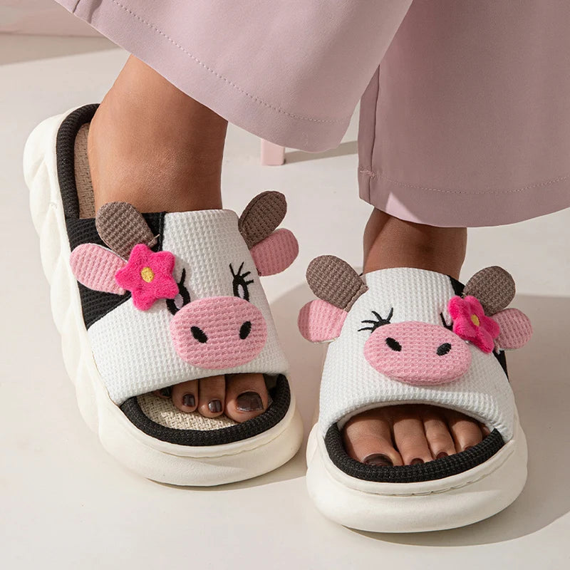 Children's cow-themed kawaii slippers with pink flowers on a neutral background