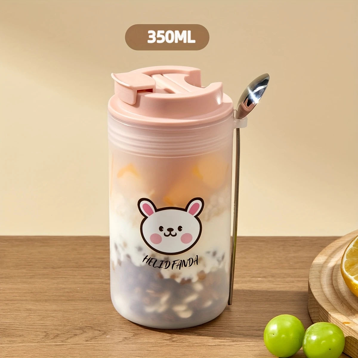 Transparent tumbler with pink lid and Kawaii cartoon character on a wooden surface