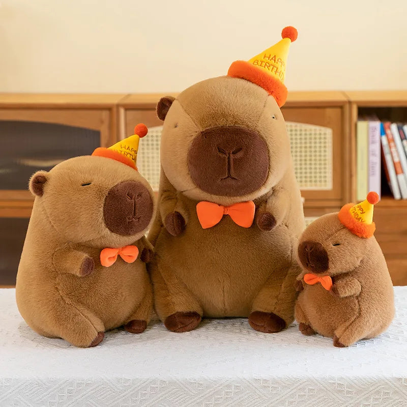 Three brown kawaii teddy bears with orange bow ties and party hats on a light surface.