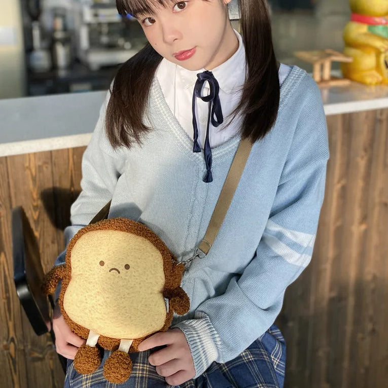 Person holding a Kawaii plush toy resembling a sandwich with a sad face in an indoor setting.