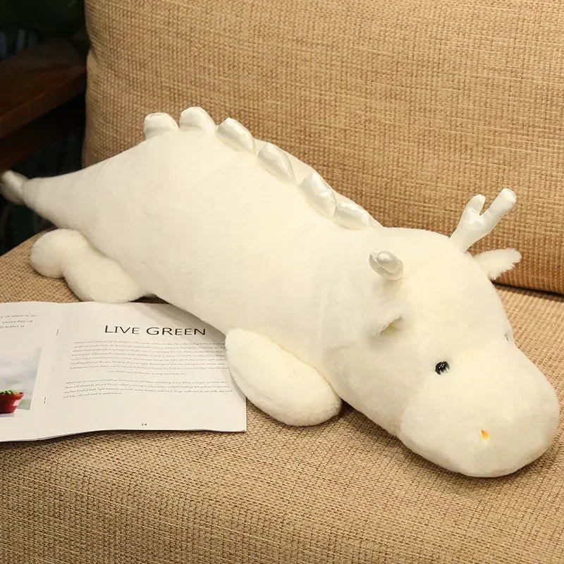 White dragon kawaii plush toy on a beige couch with a magazine underneath