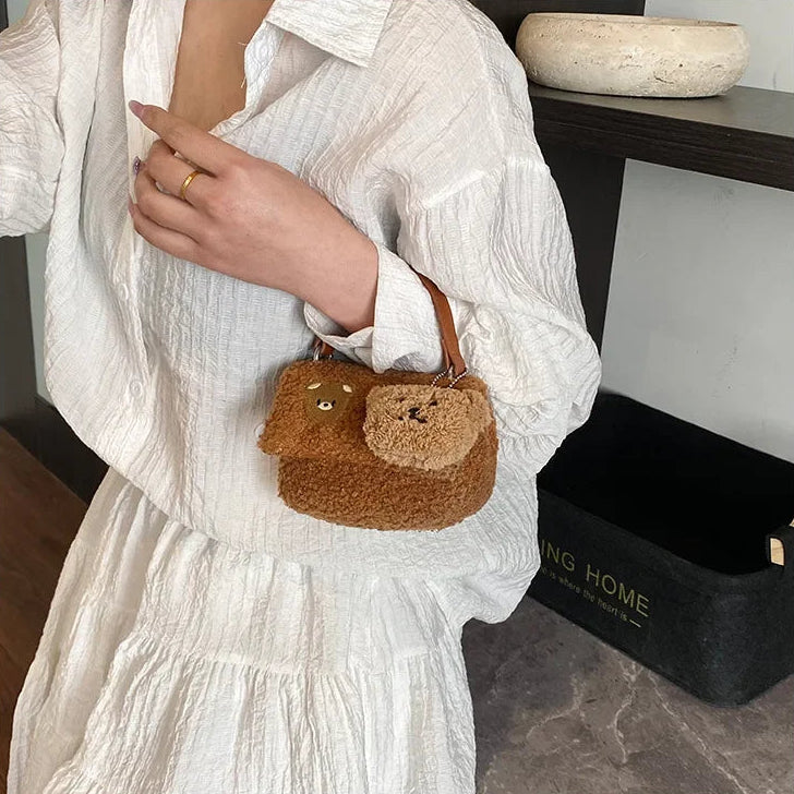 Person holding a small brown bag with Kawaii bear design indoors