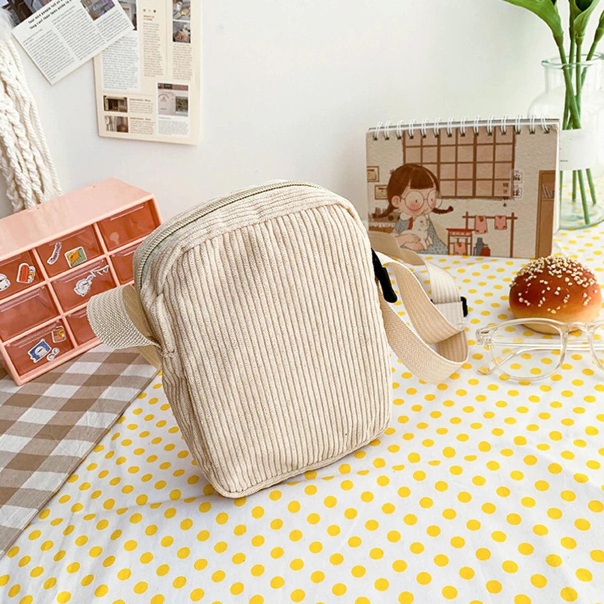Beige wedge-shaped pillow on a Kawaii polka dot tablecloth with a calendar and small suitcase in the background.