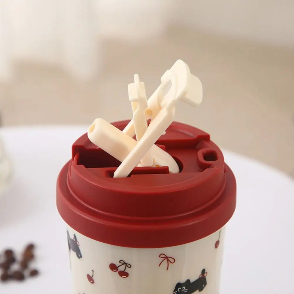 Red lid with straw holder on a white Kawaii cup with black dog illustrations