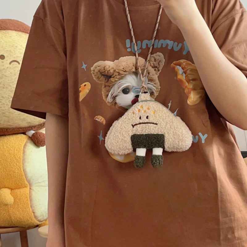Person wearing a brown t-shirt with Kawaii cartoon character design, sitting next to a plush toy.