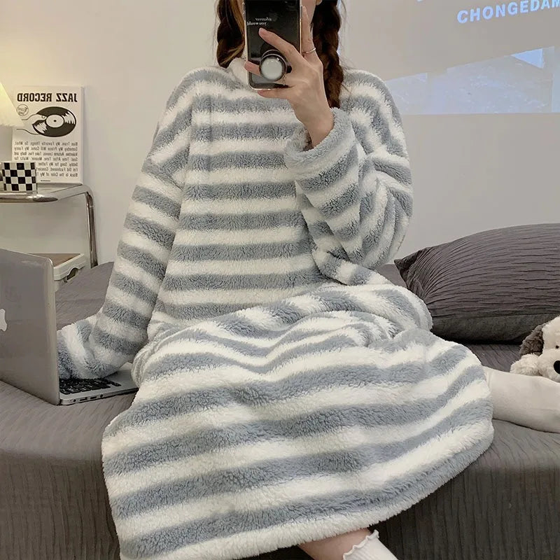 Person wearing a gray and white striped kawaii robe sitting on a bed with a laptop.