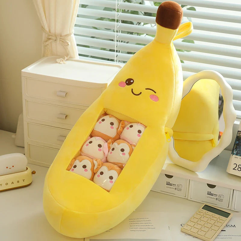 Plush banana-shaped pillow with kawaii cartoon faces on a desk