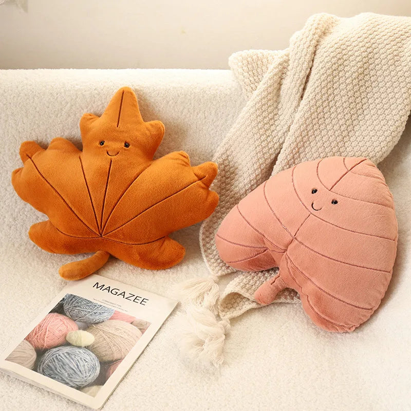 Two cute leaf-shaped kawaii cushions on a couch with a magazine underneath.