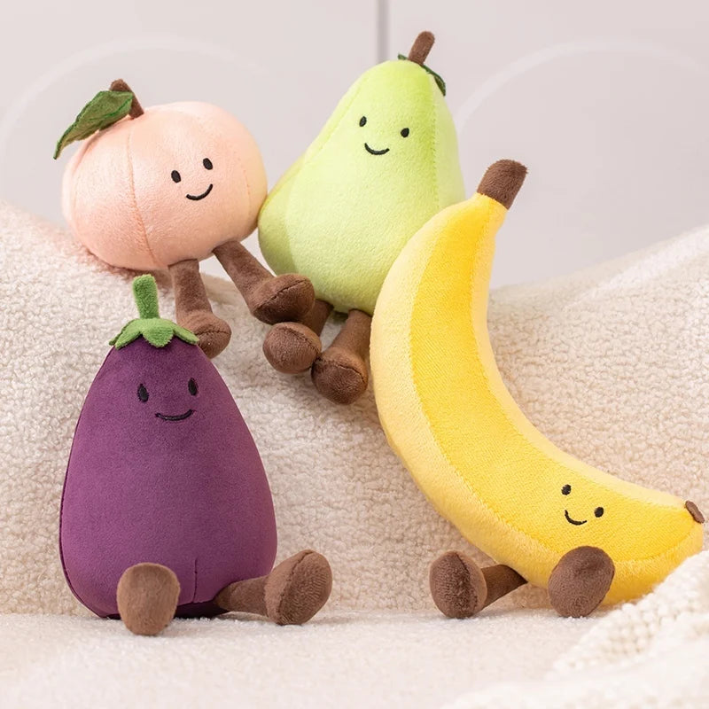 Kawaii plush toys shaped like a peach, pear, eggplant, and banana on a soft surface.