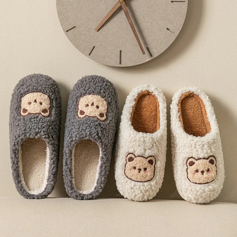 Pair of gray slippers and pair of white slippers with kawaii bear face design on a neutral background.