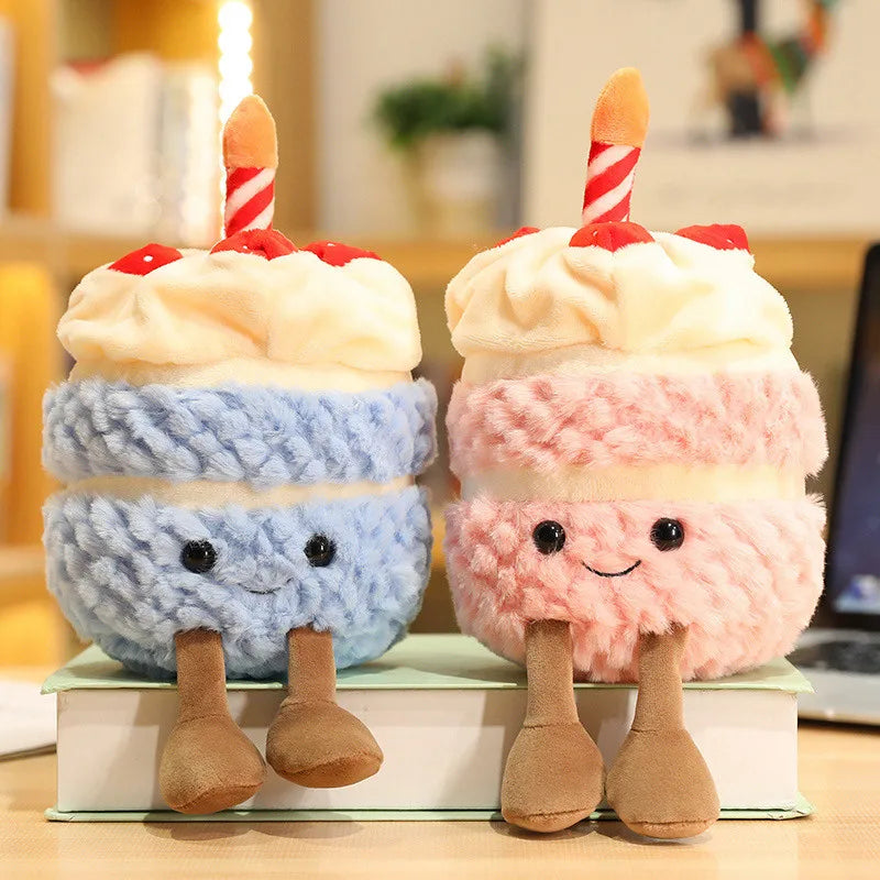 Two plush kawaii toys shaped like birthday cakes with candles on a book