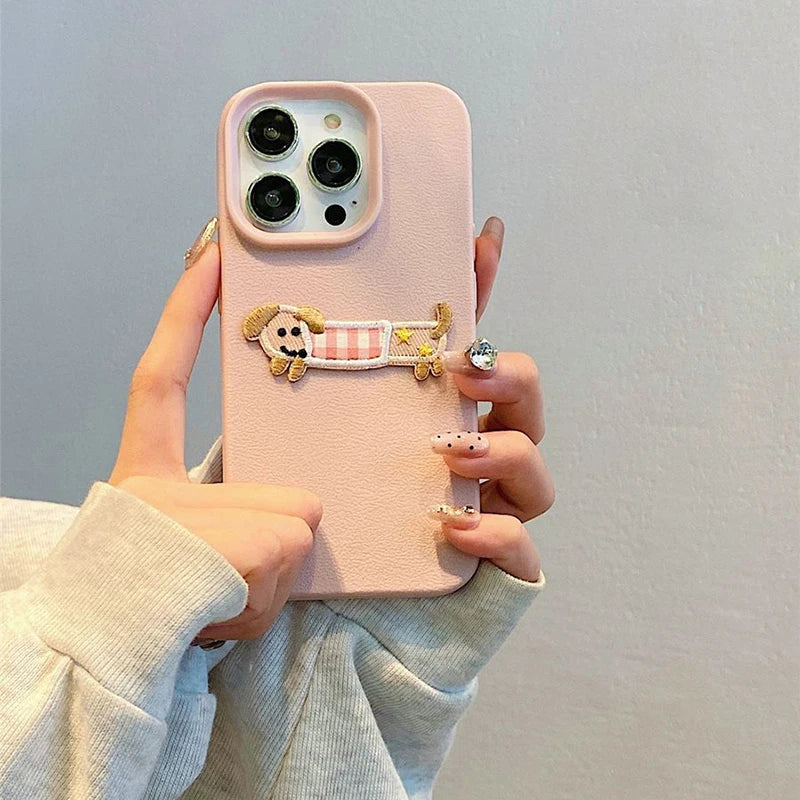Pink phone case with a kawaii decorative charm held by a person against a light gray background