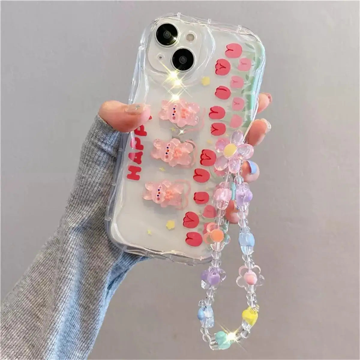 Phone case with kawaii colorful decorations and a chain held by a hand against a gray background