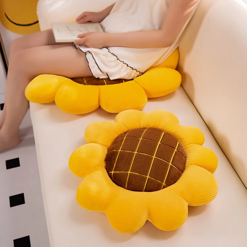 Yellow sunflower-shaped kawaii cushion on a sofa with a person reading a book.