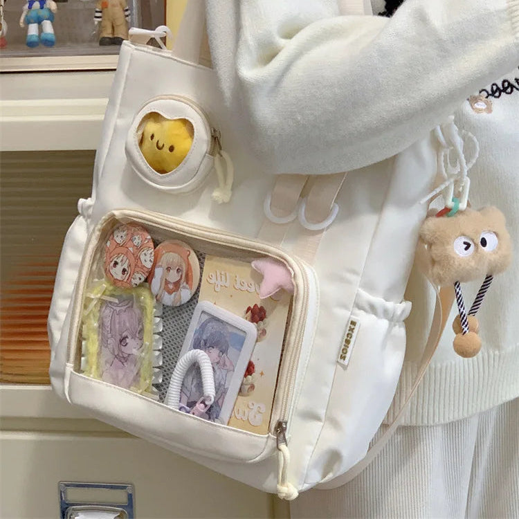 White Kawaii backpack with cute design and accessories, worn by a person.