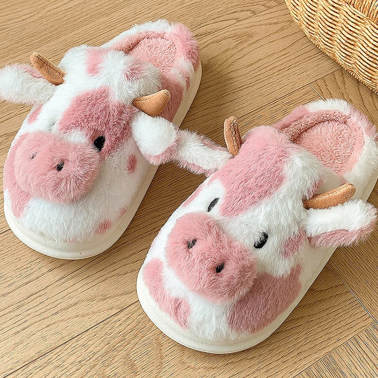 Pair of pink kawaii cow-themed slippers on a wooden floor