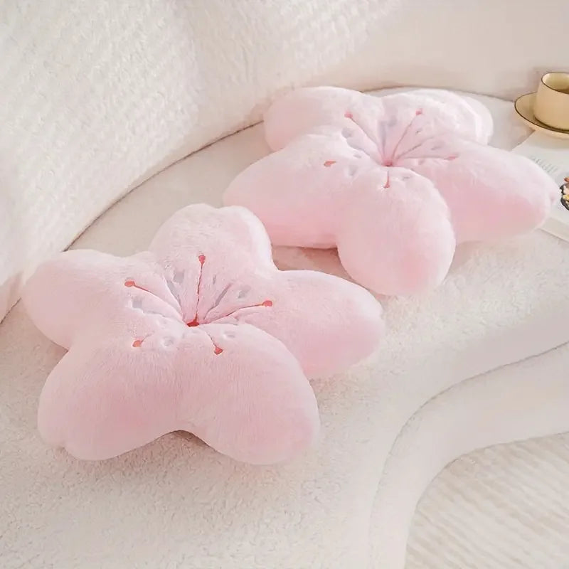 Two pink decorative pillows shaped like Kawaii cherry blossoms on a white surface.