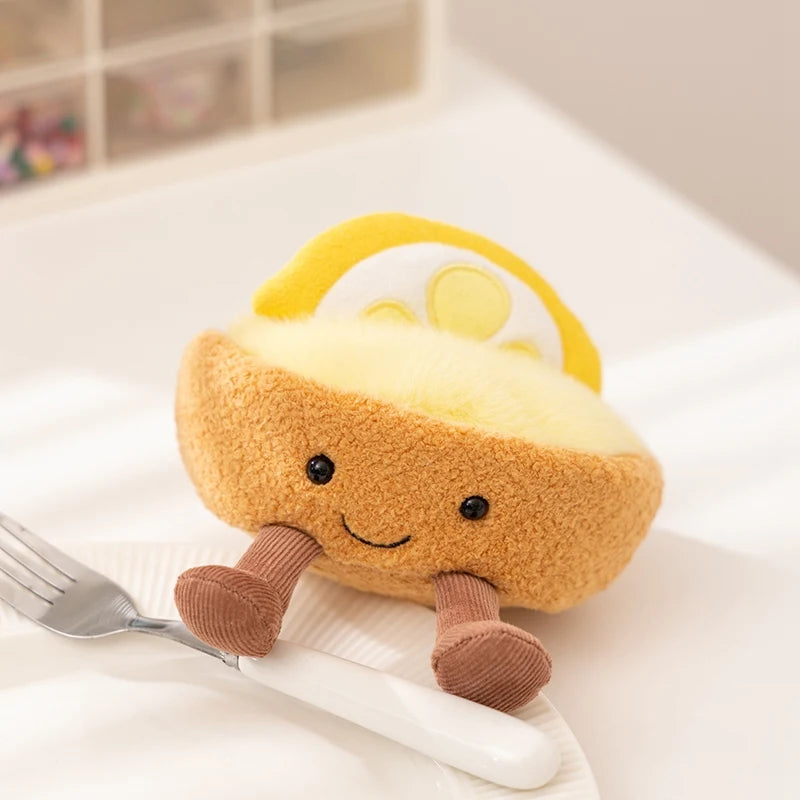 Plush kawaii toy resembling a piece of bread with a smiley face on a white surface with a fork.