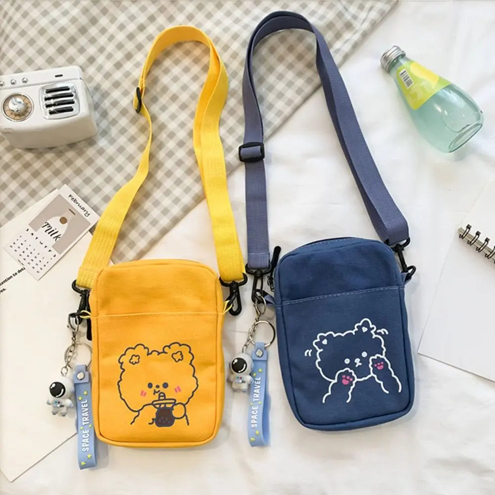 Two small shoulder bags, one yellow and one blue, with Kawaii cartoon character designs on a checkered fabric background.